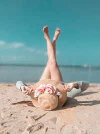 Full length of carefree woman with feet up lying on sand at beach