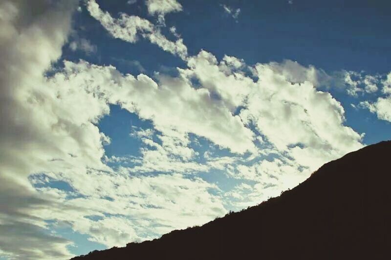 sky, cloud - sky, scenics, tranquility, mountain, low angle view, cloud, tranquil scene, beauty in nature, silhouette, nature, cloudy, blue, mountain range, outdoors, no people, idyllic, day, landscape, cloudscape