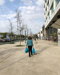 Rear view of woman on street in city against sky