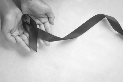 Close-up of hand holding paper over white background