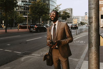 Male entrepreneur looking away while standing on footpath in city