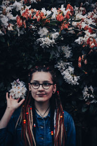 Portrait of young woman standing amidst flowers