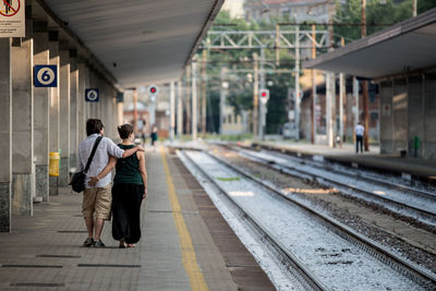 Rear view of couple walking at railroad station platform