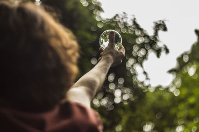 Rear view of child holding crystal ball against tree