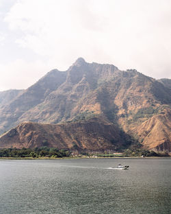 Scenic view of sea by mountains against sky