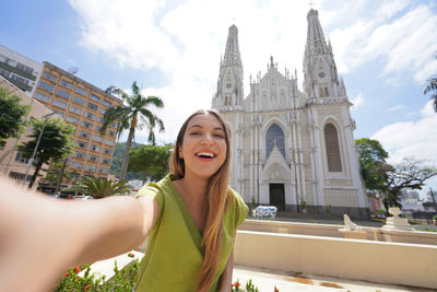 Traveler woman taking self portrait with vitoria cathedral on the background, espirito santo, brazil