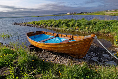 Boat moored on sea shore against sky