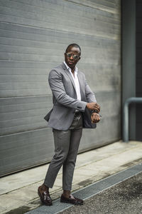 Full length of a young man standing against wall