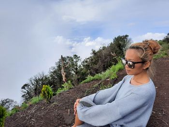 Young woman wearing sunglasses standing against sky