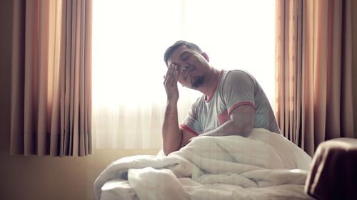 Portrait of man sitting on bed at home