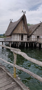 Wooden house by lake against sky