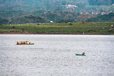 Scenic view of people on river against trees