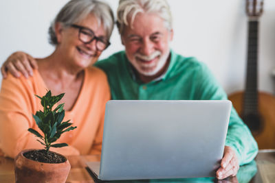 Smiling couple using laptop while sitting at home