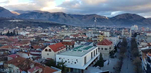 Aerial view of townscape and mountains against sky