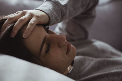 Close-up of worried woman lying on sofa at home