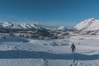 An unrecognizable male hiker wearing snowshoes walking in the french alps