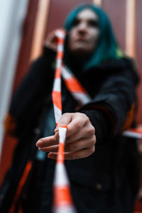 Low angle view of young woman with dyed hair holding ribbon while standing at home