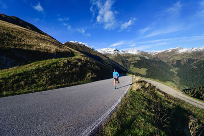 Rear view of people walking on road against sky