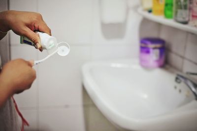 Cropped hands of person putting toothpaste on toothbrush