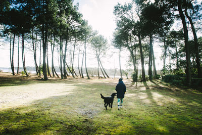 Rear view of woman with dog on landscape against sky