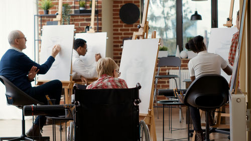 Rear view of woman drawing on canvas