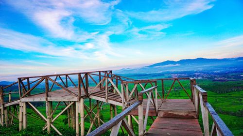 Pier on landscape against blue sky