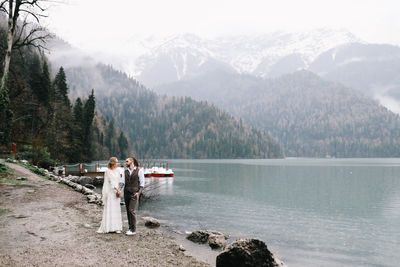 A loving married couple the bride and groom in suits celebrate wedding near the mountains and water