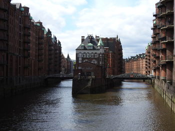 Canal amidst buildings in city against sky