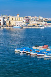 Sailboats moored on sea against buildings in city