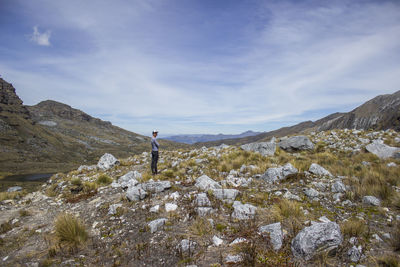 Man standing on rock against sky