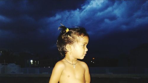 Portrait of shirtless boy looking away against sky
