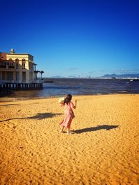 Full length of woman on beach against clear sky