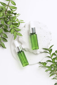 Green glass dropper bottles on concrete podium with leaves. cosmetic container mock-ups.