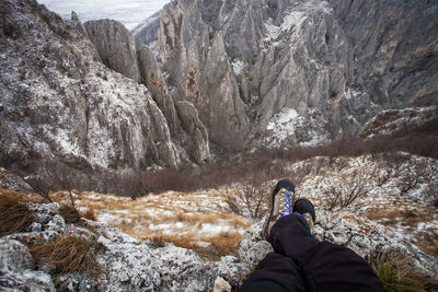 Low section of man sitting on cliff during winter