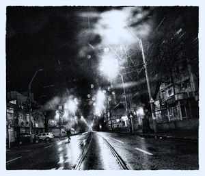 Street amidst illuminated city against sky at night