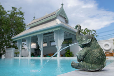 Statue by swimming pool against sky
