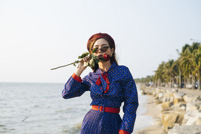 Full length of woman standing at beach against clear sky