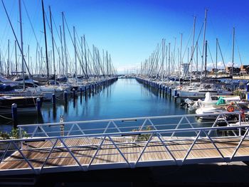 Sailboats moored at harbor against clear blue sky