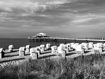 Hooded chairs on beach against sky