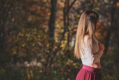 Rear view of woman standing against trees in forest