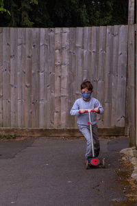 Full length of boy standing against fence