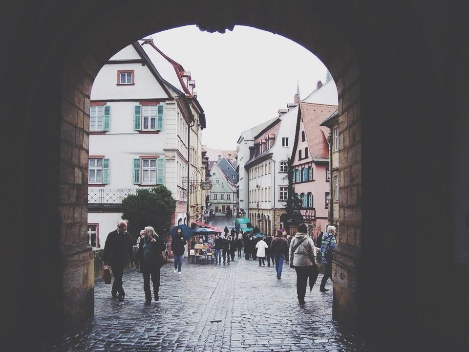 architecture, built structure, men, walking, building exterior, person, lifestyles, arch, the way forward, large group of people, street, full length, leisure activity, city life, rear view, cobblestone, building, group of people, city