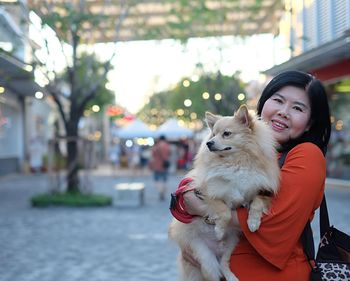 Portrait of woman with dog in city