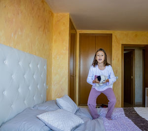 Portrait of girl holding toy while jumping on bed