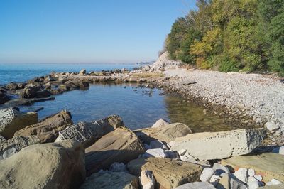 Rocks by sea against clear sky