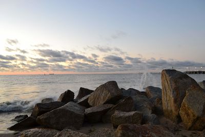 Rocks on beach against sky during sunset