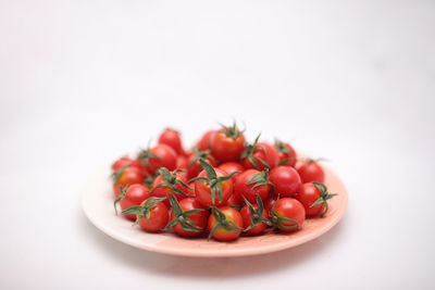 Close-up of cherries in plate against white background