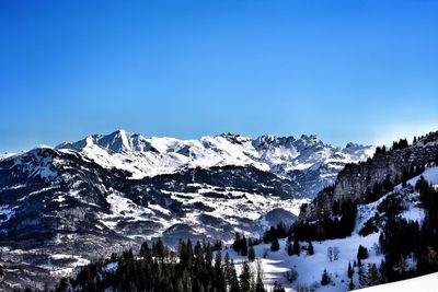 Scenic view of snowcapped mountains against blue sky