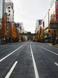 Road by buildings against sky in city