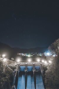 Illuminated bridge over river against sky at night